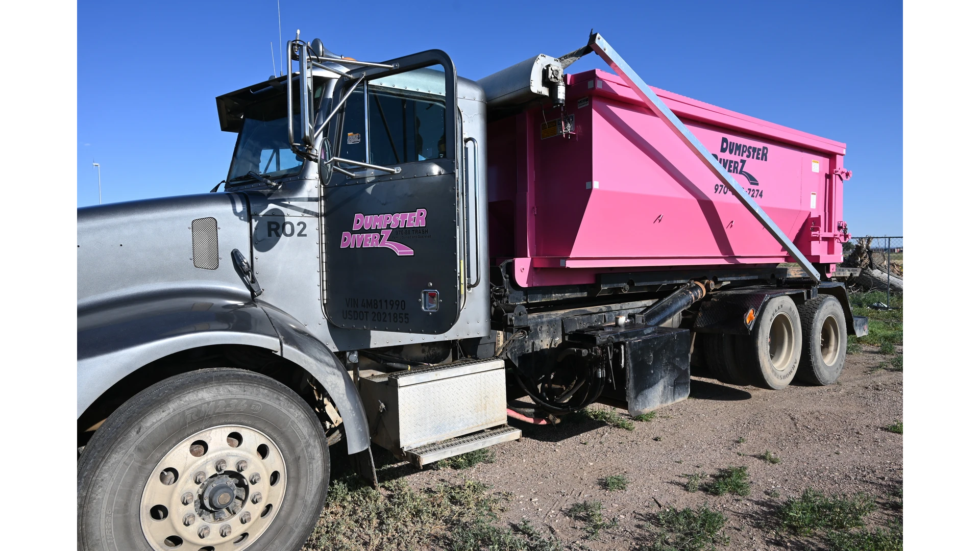 Dumpster Diverz pink garbage truck and bin curbside for residential trash pickup